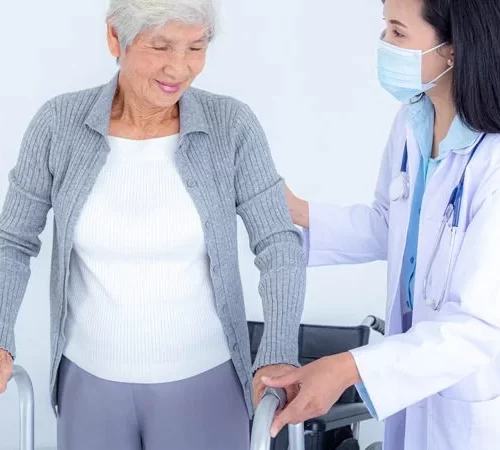 Kalça Kırığı Ameliyatı Sonrası Doktor Eşliğinde Yürüyen Yaşlı Kadın