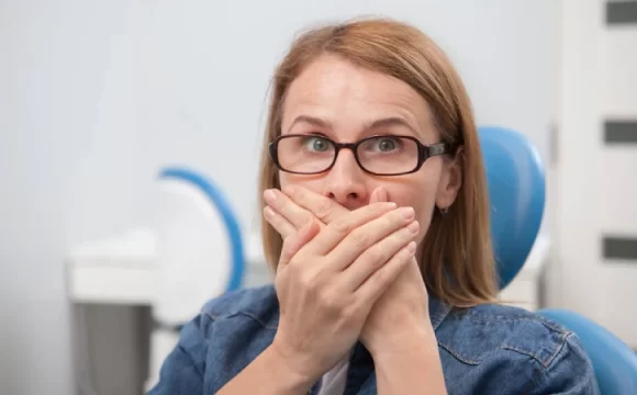 ağız kokusu nedeniyle ağzını kapatan gözlüklü kadın