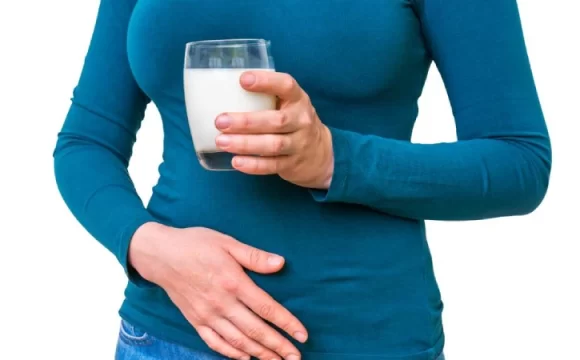 laktoz intoleransı nedeniyle karnı ağrıyan elinde süt tutan kadın