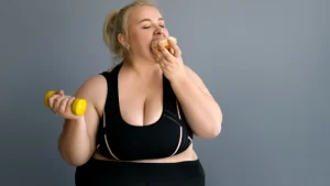 Obezite Ameliyatlarının Yan Etkileri Nelerdir? obez kadın bir elinde dumbel diğer elinde donut