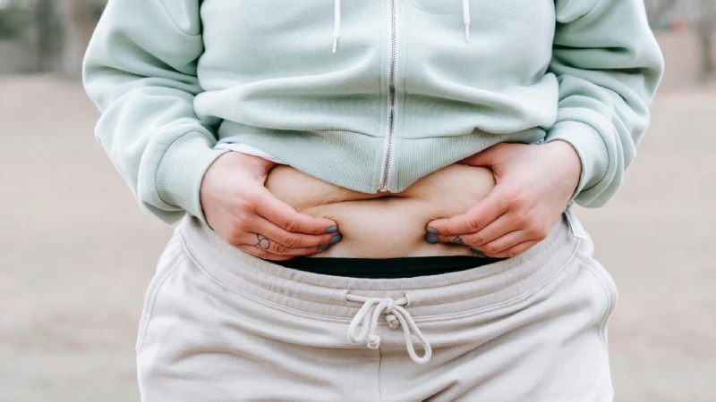 Obezite Nedenleri- obez ve göbeğini tutan kadın